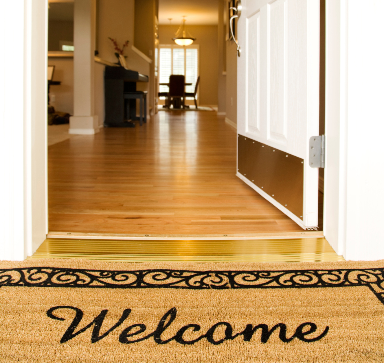 "Welcome" mat in front of white open door